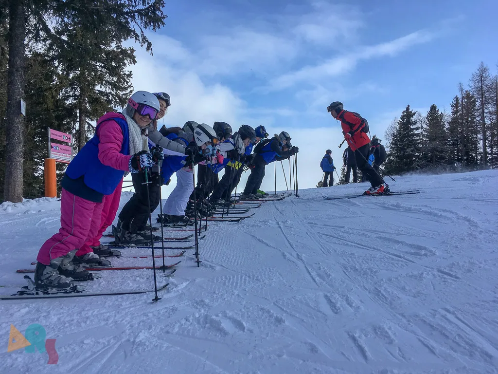 Skigruppe wartet nebeneinander auf der Piste.